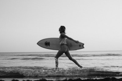 On the beach with a surf board the grayscale image of women
